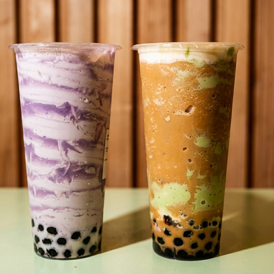 Two tall bubble tea drinks, one purple taro and one brown matcha, with tapioca pearls.